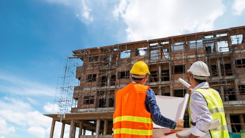 Businessman engineer looking blueprint in a building to  discussion with architects at construction site or building site of highrise building