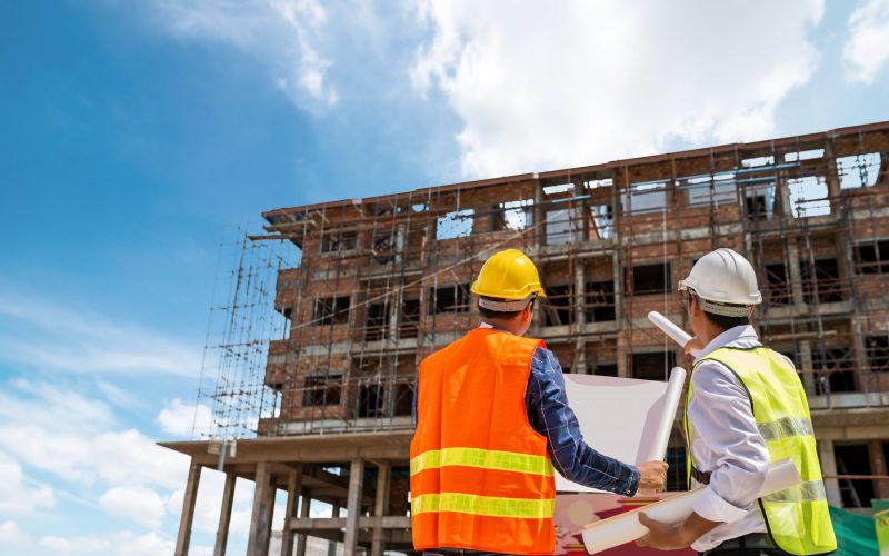 Businessman engineer looking blueprint in a building to  discussion with architects at construction site or building site of highrise building