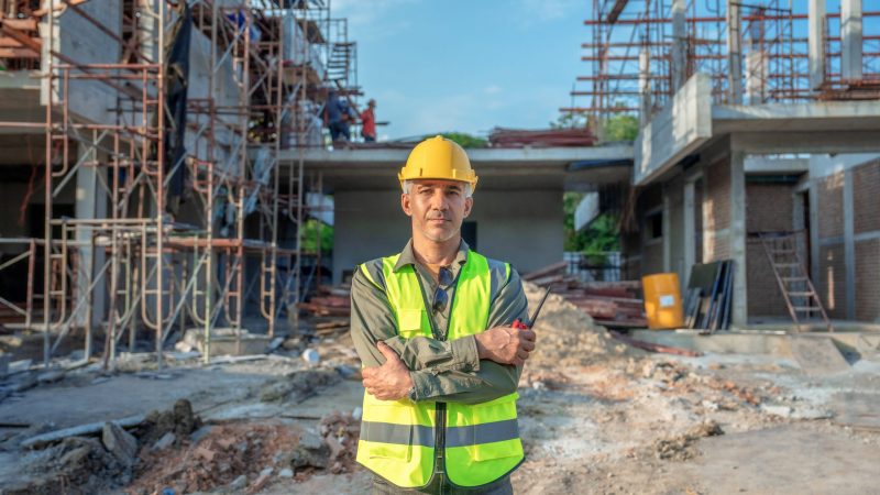Portrait of Caucasian male worker in front of construction site.